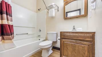Ein Badezimmer mit Badewanne, Toilette und einem Holzwaschtisch.