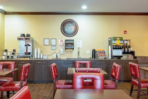 Un restaurant avec un comptoir, des machines à café et des fauteuils en cuir rouge.