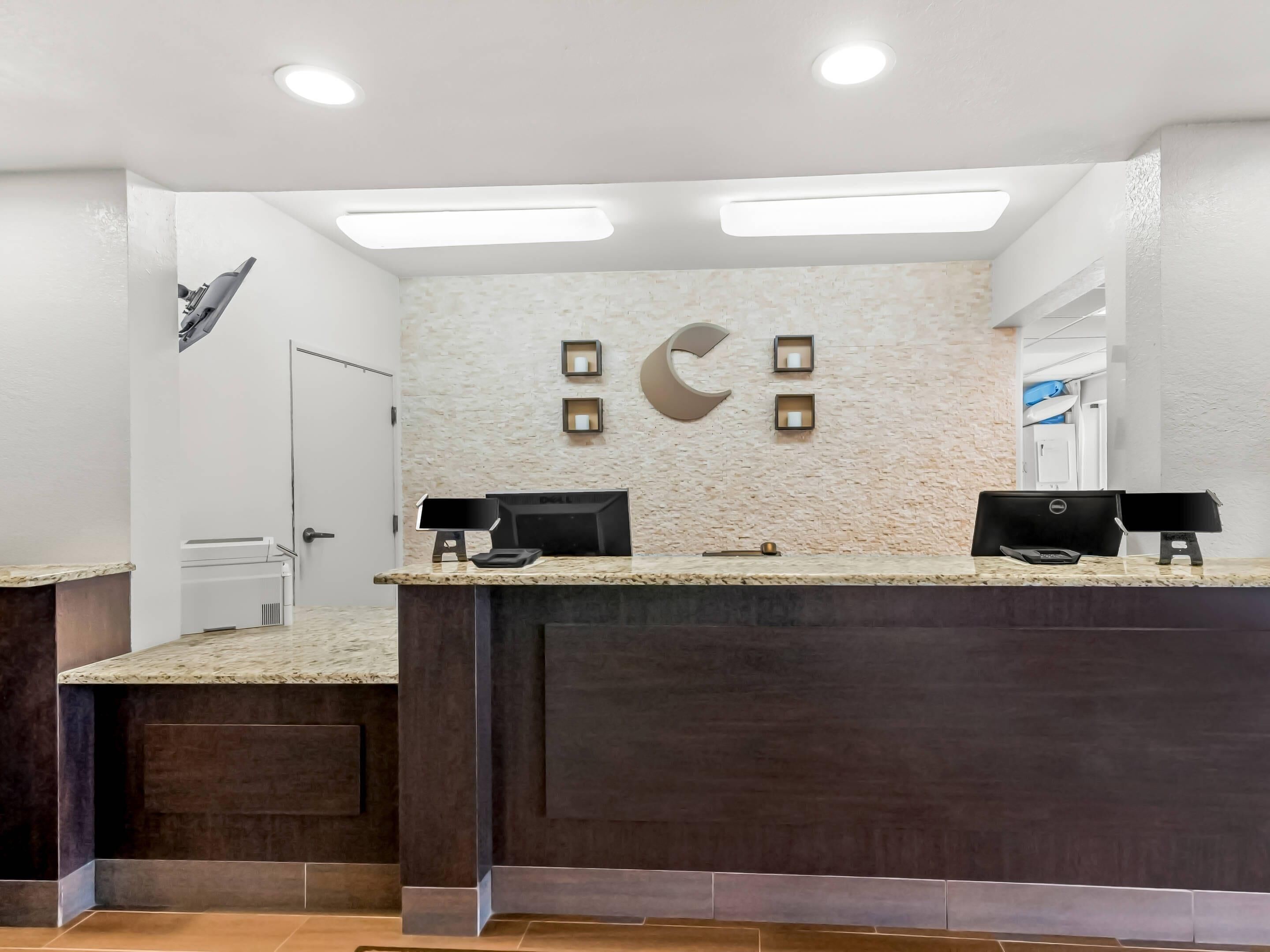 A reception desk with two computer monitors, a marble countertop, and a textured wall with a crescent moon design.