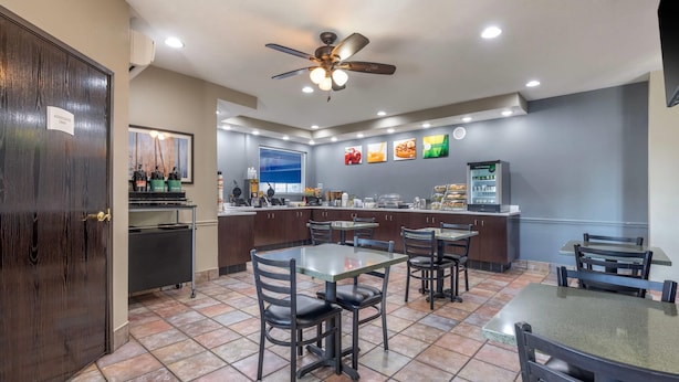 A restaurant with a counter, tables, chairs, a ceiling fan, and a tiled floor.