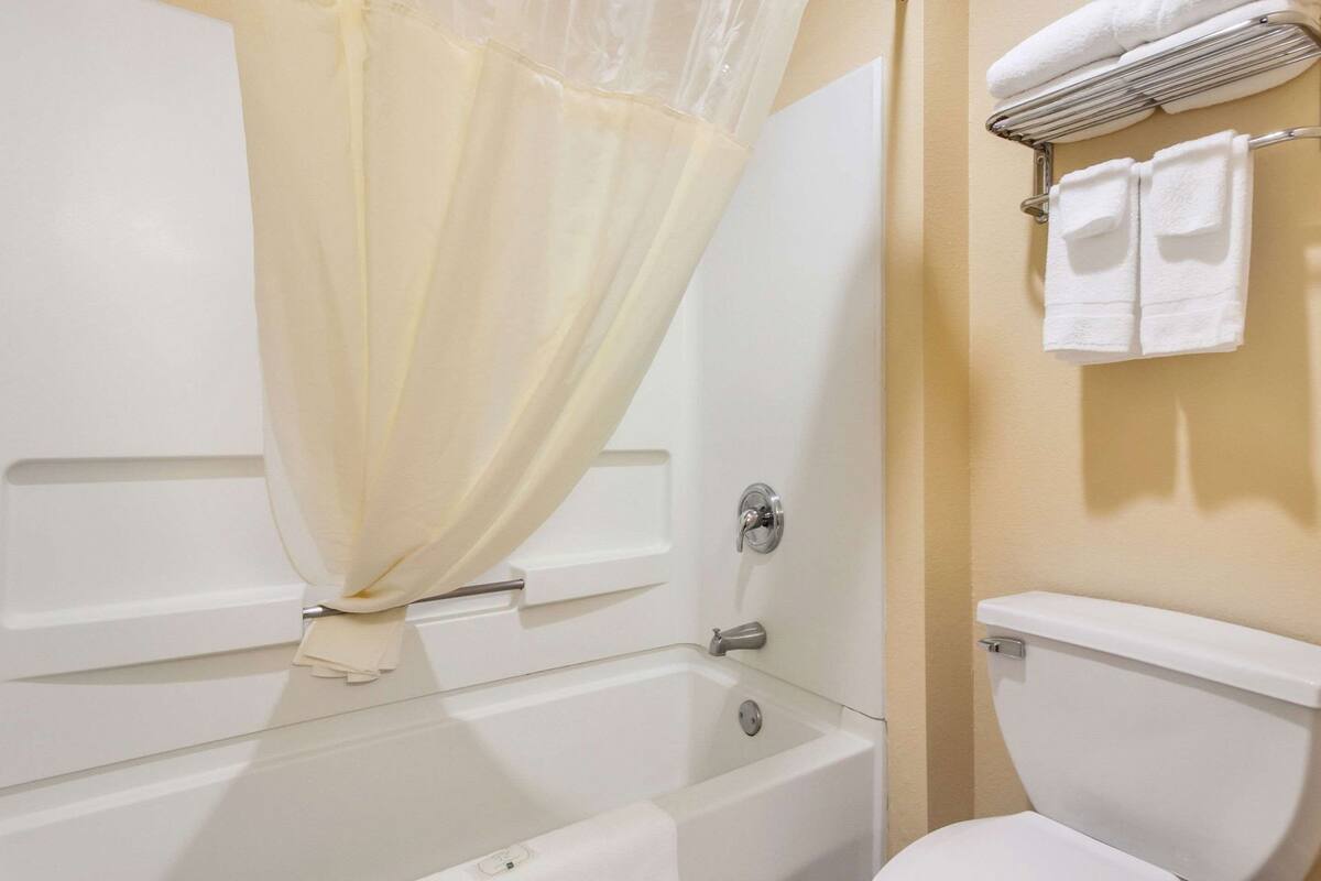 A bathroom with a bathtub, toilet, and a towel rack with towels.