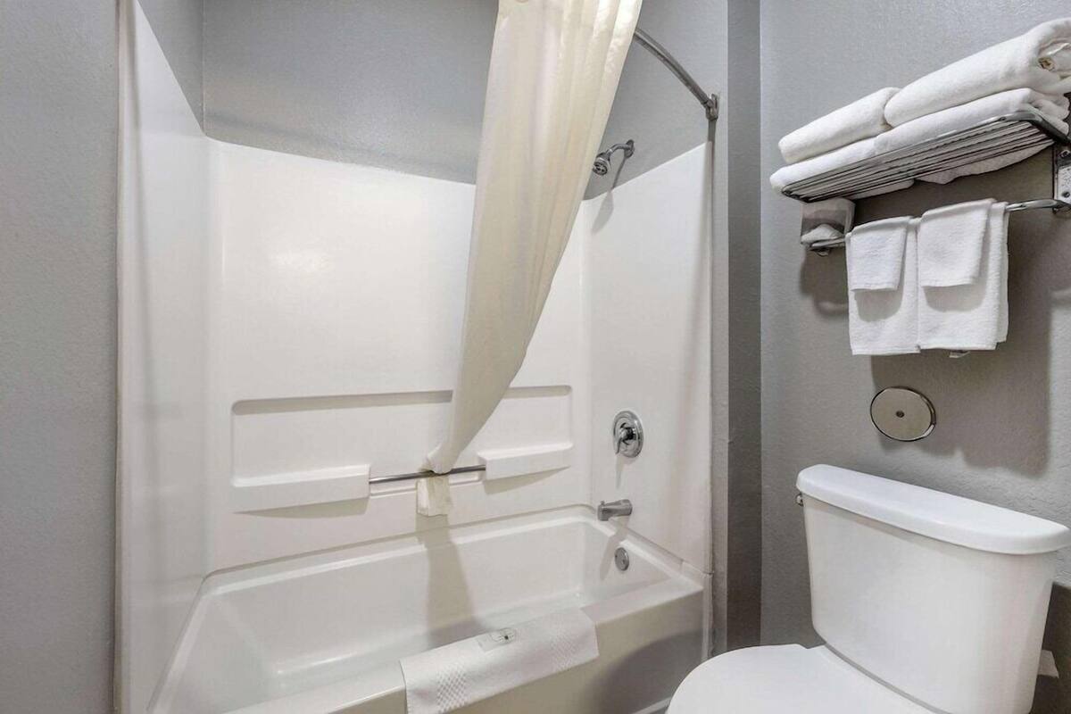 A bathroom with a bathtub, toilet, and towel rack.