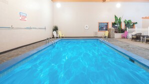 Ein Schwimmbecken mit Rettungsschwimmer-Schild, Liegestühlen und Topfpflanzen.