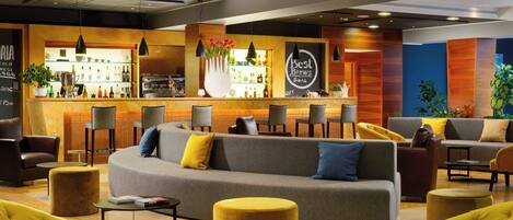 Un área de estar moderna con un bar, sofás y sillones.
