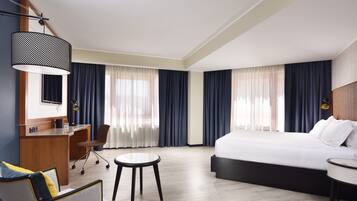 A hotel room with a bed, desk, chair, and a small table.