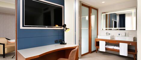 Una habitación de hotel moderna con escritorio, silla y un espejo grande sobre el tocador.