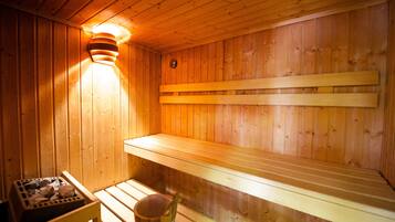 A wooden sauna with benches and a bucket.
