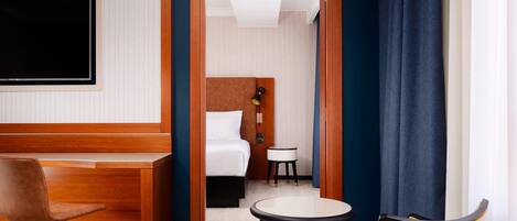 Una habitación de hotel con una cama, un escritorio, una silla y una mesita.