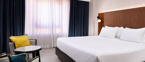 A hotel room with a large bed, a round table, and two chairs.