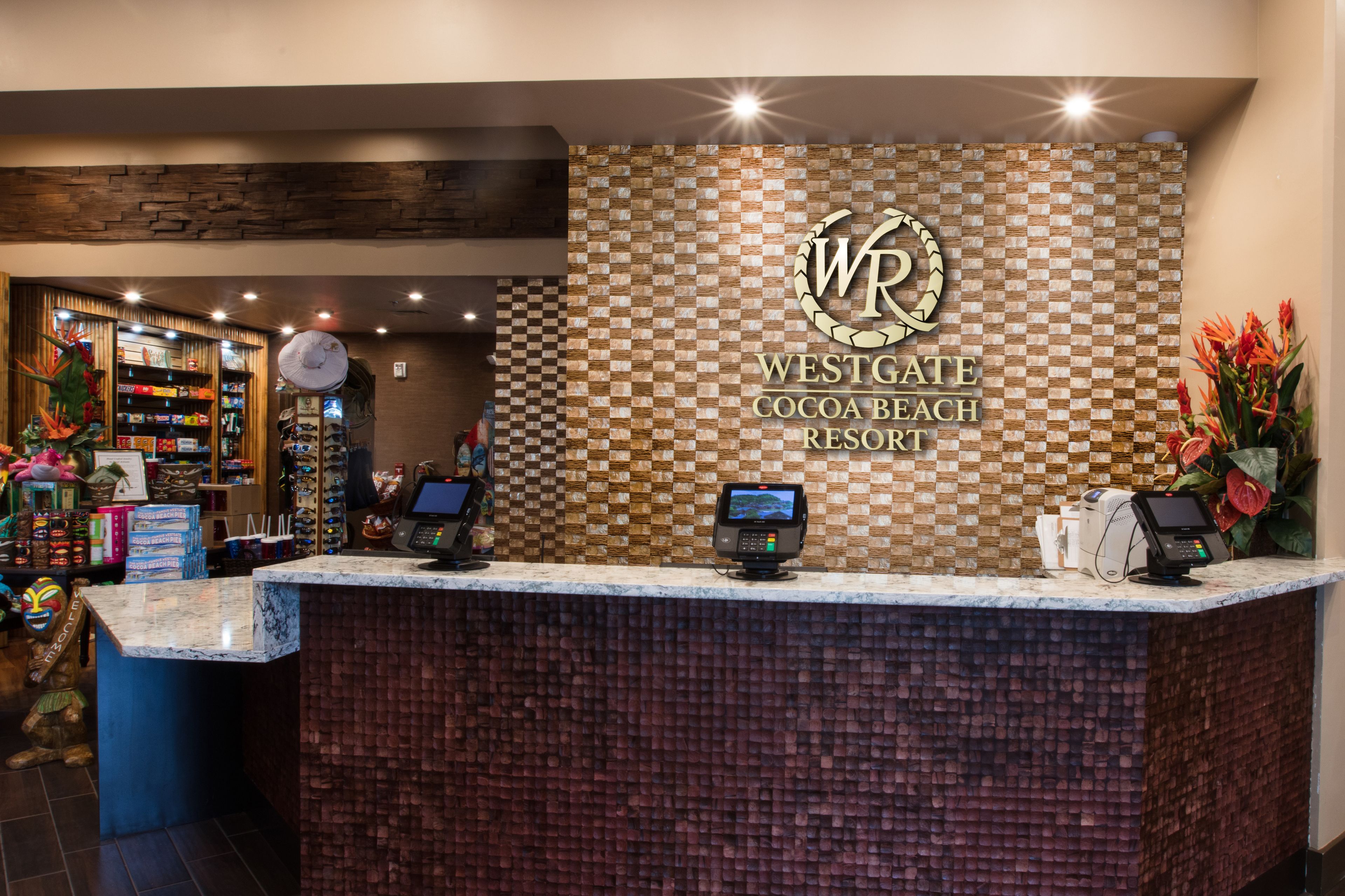 Ein Empfangsbereich im Westgate Cocoa Beach Resort mit Wandgestaltung in Schachbrettoptik, einer digitalen Kiosk und verschiedenen Annehmlichkeiten im Hintergrund.