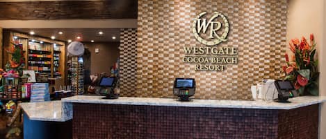Ein Empfangsbereich im Westgate Cocoa Beach Resort mit Wandgestaltung in Schachbrettoptik, einer digitalen Kiosk und verschiedenen Annehmlichkeiten im Hintergrund.