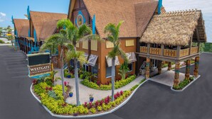 A resort with a thatched-roof building, palm trees, and a sign reading "Westgate Cocoa Beach Resort". - Westgate Cocoa Beach Resort (Cocoa Beach)