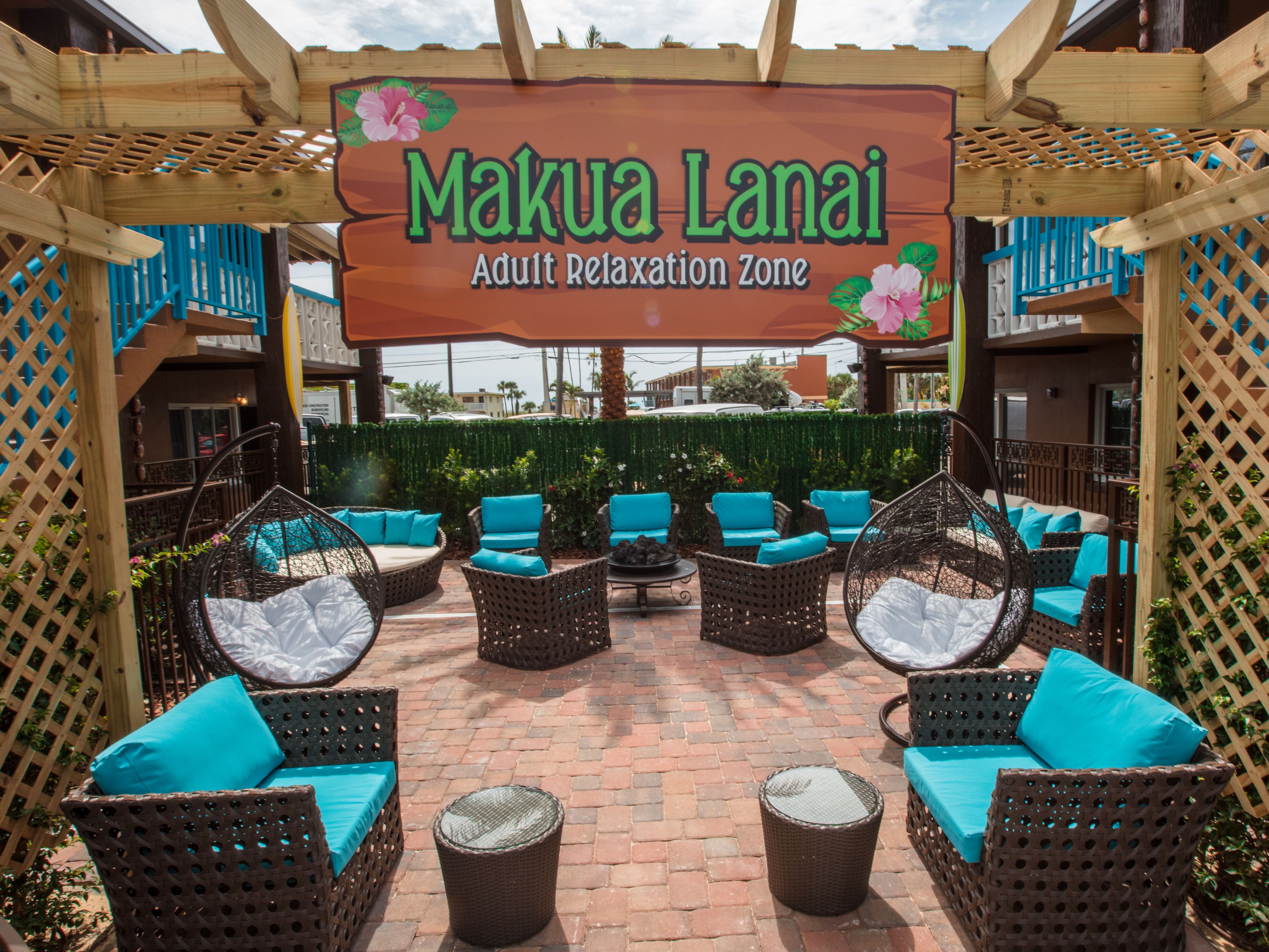 An outdoor seating area with wicker furniture and a sign reading "Makua Lanai Adult Relaxation Zone".