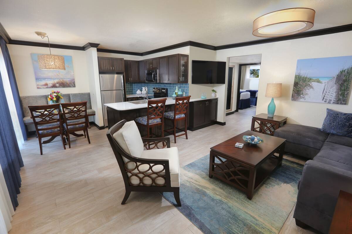 A modern living room with a sofa, coffee table, and dining area with chairs.