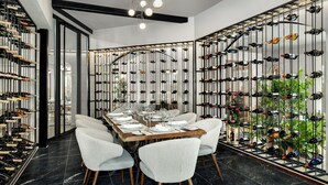 A dining area with a long table set for six, surrounded by white upholstered chairs.