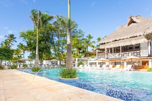 Uma área de piscina com espreguiçadeiras e um edifício com telhado de palha.