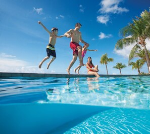 A clear blue pool with three people jumping.