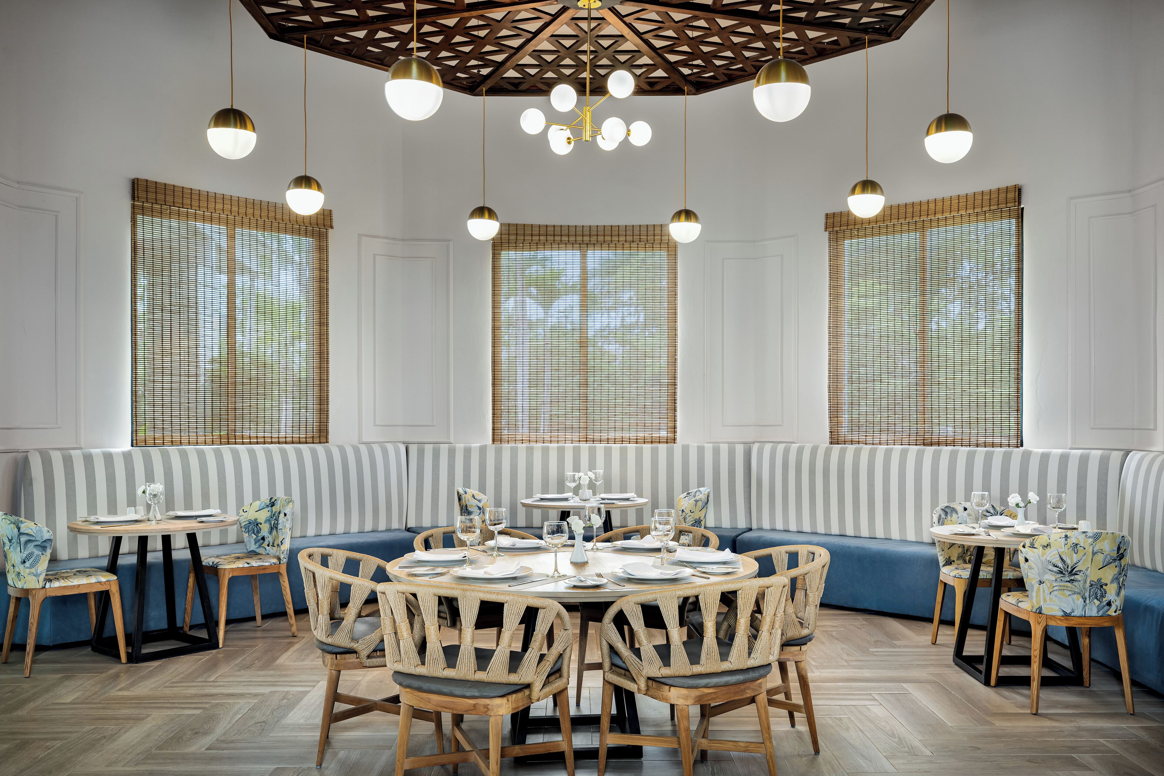 A dining area with a round table set for six, surrounded by blue upholstered seating.