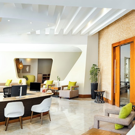 A modern living area with a curved sofa, a dining table with chairs, and a kitchen in the background.