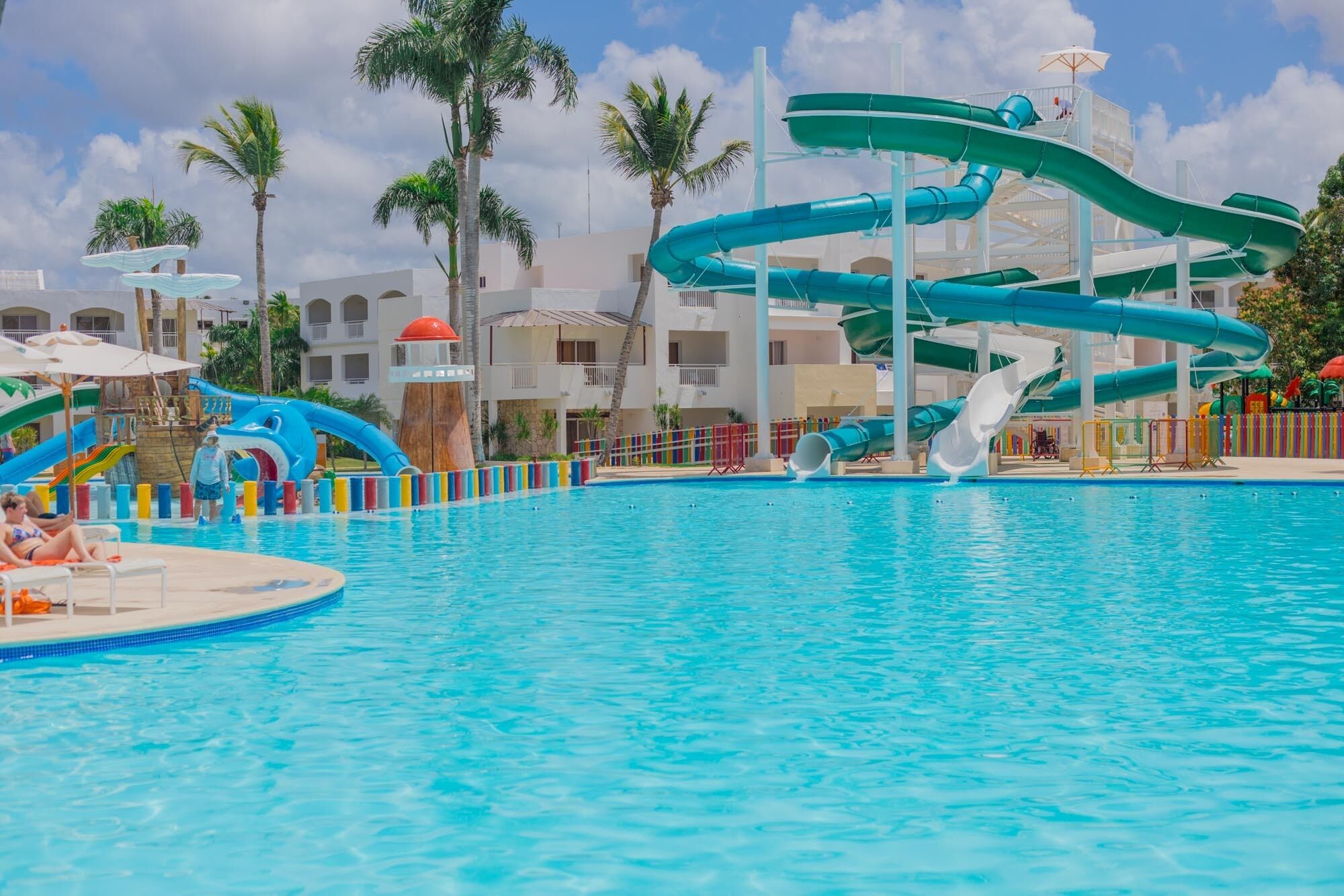 A swimming pool with multiple water slides and a poolside area with lounge chairs.
