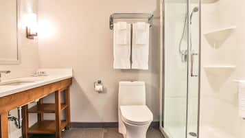 Un baño moderno con tocador de madera, inodoro, cabina de ducha con vidrio y barra para toallas.