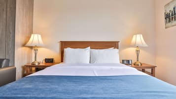 Een hotelkamer met een groot bed, twee nachtkastjes met lampen, een stoel en een schilderij aan de muur.