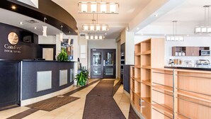 Un espace d’accueil d’hôtel au design moderne, comprenant un comptoir d’accueil, un espace d’attente et un coin cuisine.