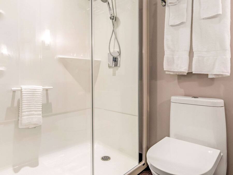 A modern bathroom with a glass-enclosed shower, a white toilet, and a towel rack.