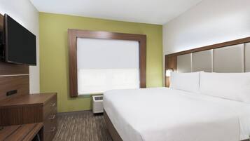 Una habitación de hotel con cama, televisor, cómoda y ventana con persianas.