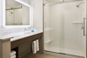 A modern bathroom with a glass-enclosed shower, a white sink, and a large mirror. - Holiday Inn Express & Suites Columbus Airport East by IHG (Columbus)
