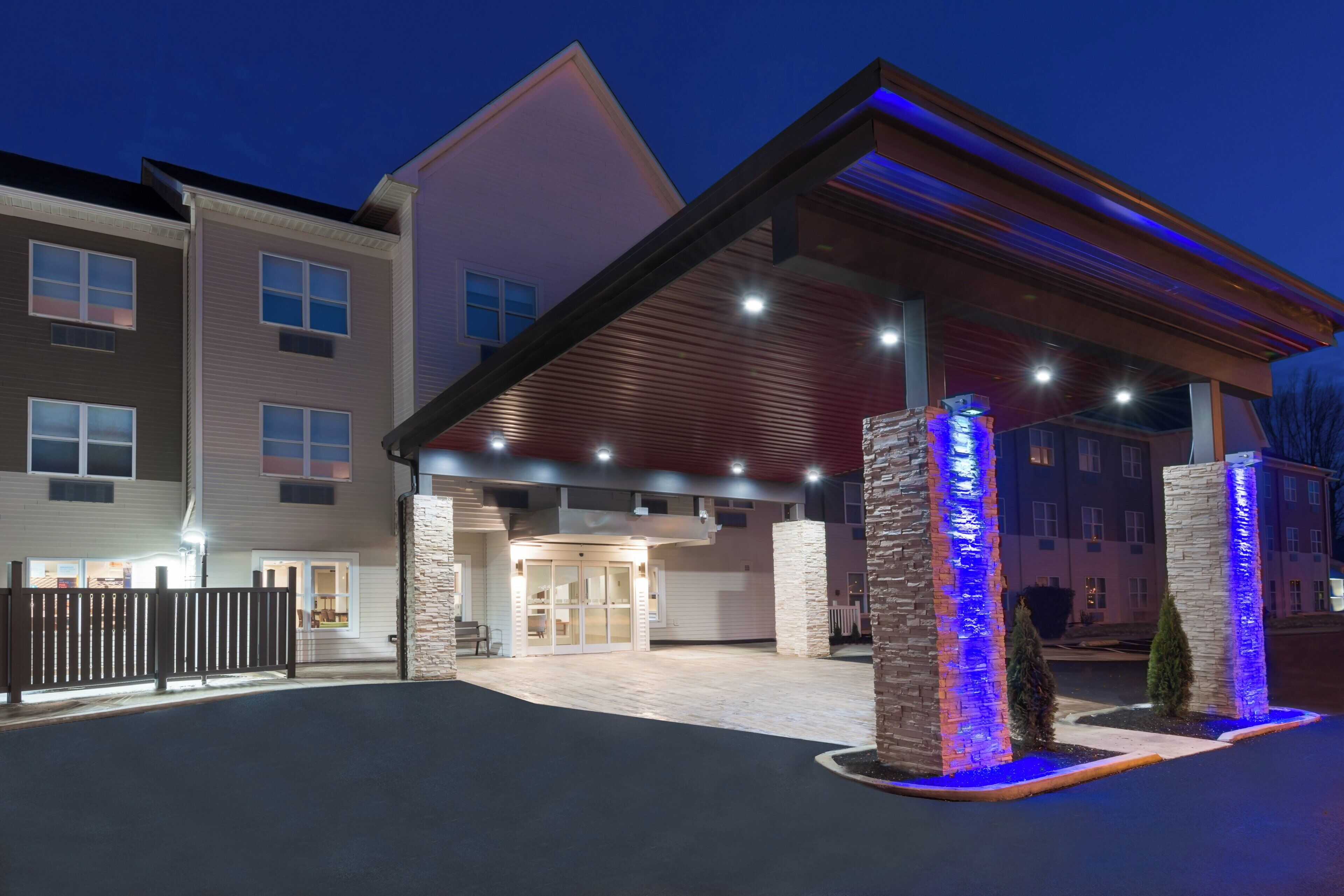 A hotel entrance with a covered walkway, stone pillars, and a gated driveway.