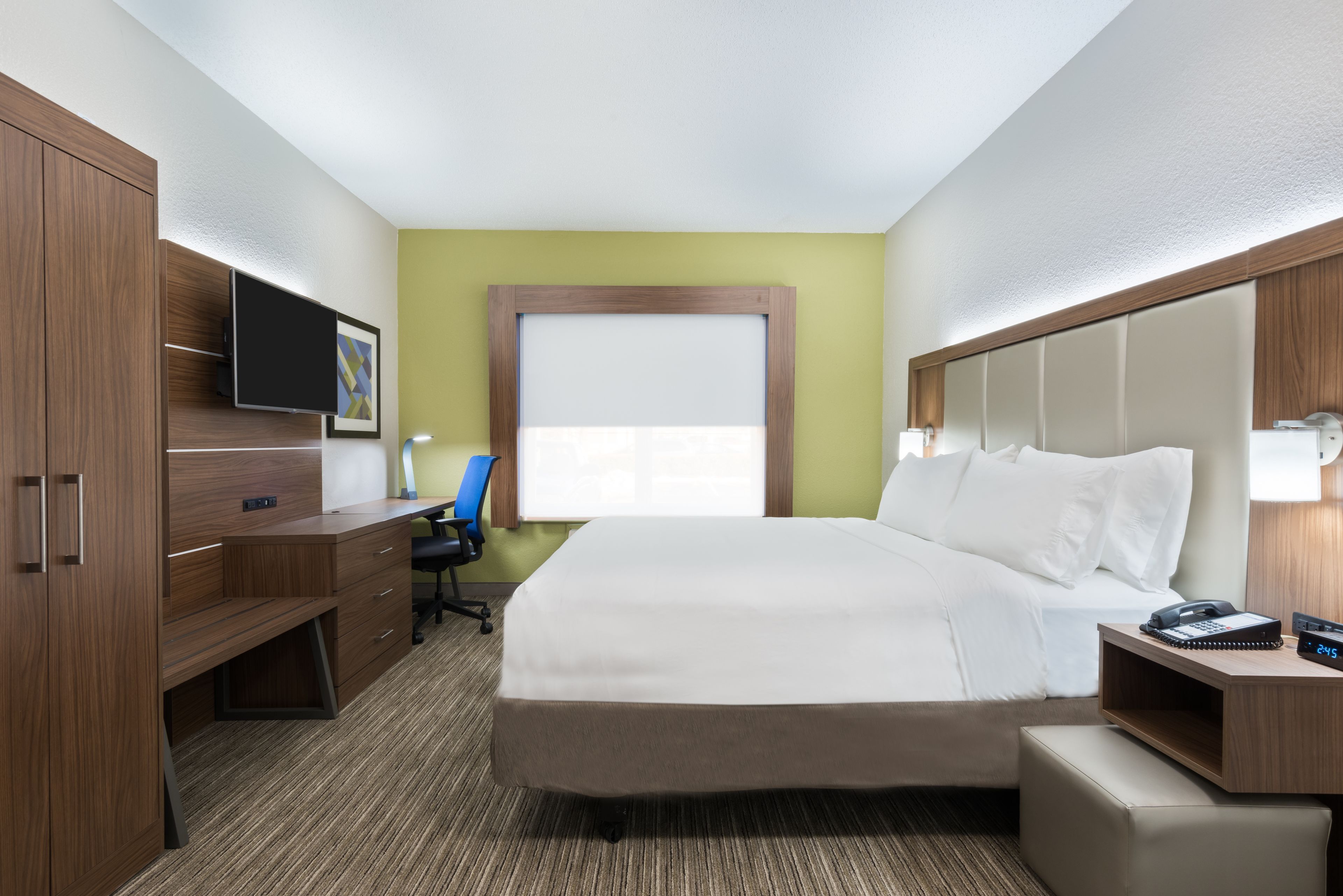Una habitación de hotel con una cama, un escritorio, una silla, un televisor y una ventana.