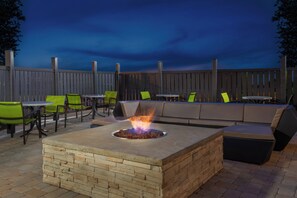 An outdoor patio with a fire pit, seating, and a wooden fence. - Holiday Inn Express & Suites Columbus Airport East by IHG (Columbus)