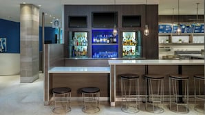Un área de bar moderna con mostrador, taburetes y estanterías llenas de botellas.