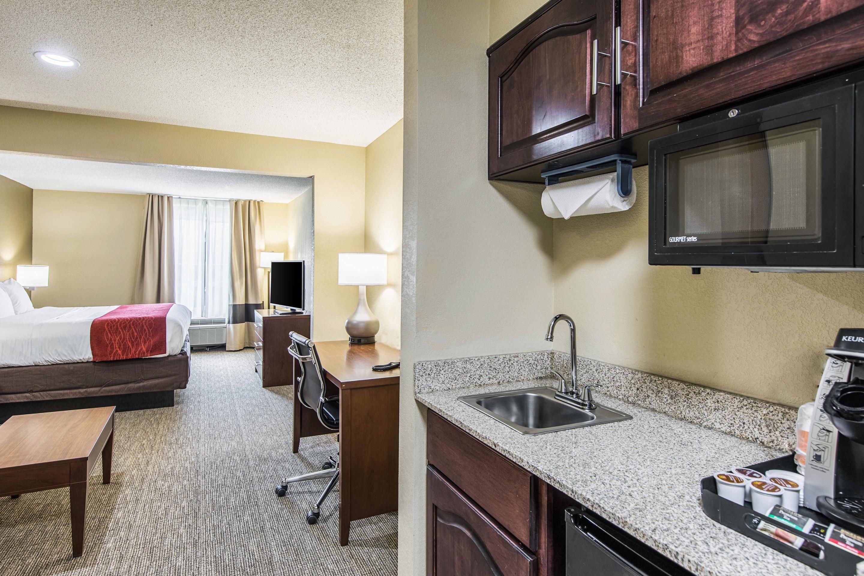 Une chambre d’hôtel équipée d’un lit, d’un bureau, d’une chaise, d’une lampe et d’une kitchenette.