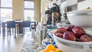Un buffet de petit-déjeuner proposant des fruits, des machines à café et un espace détente.