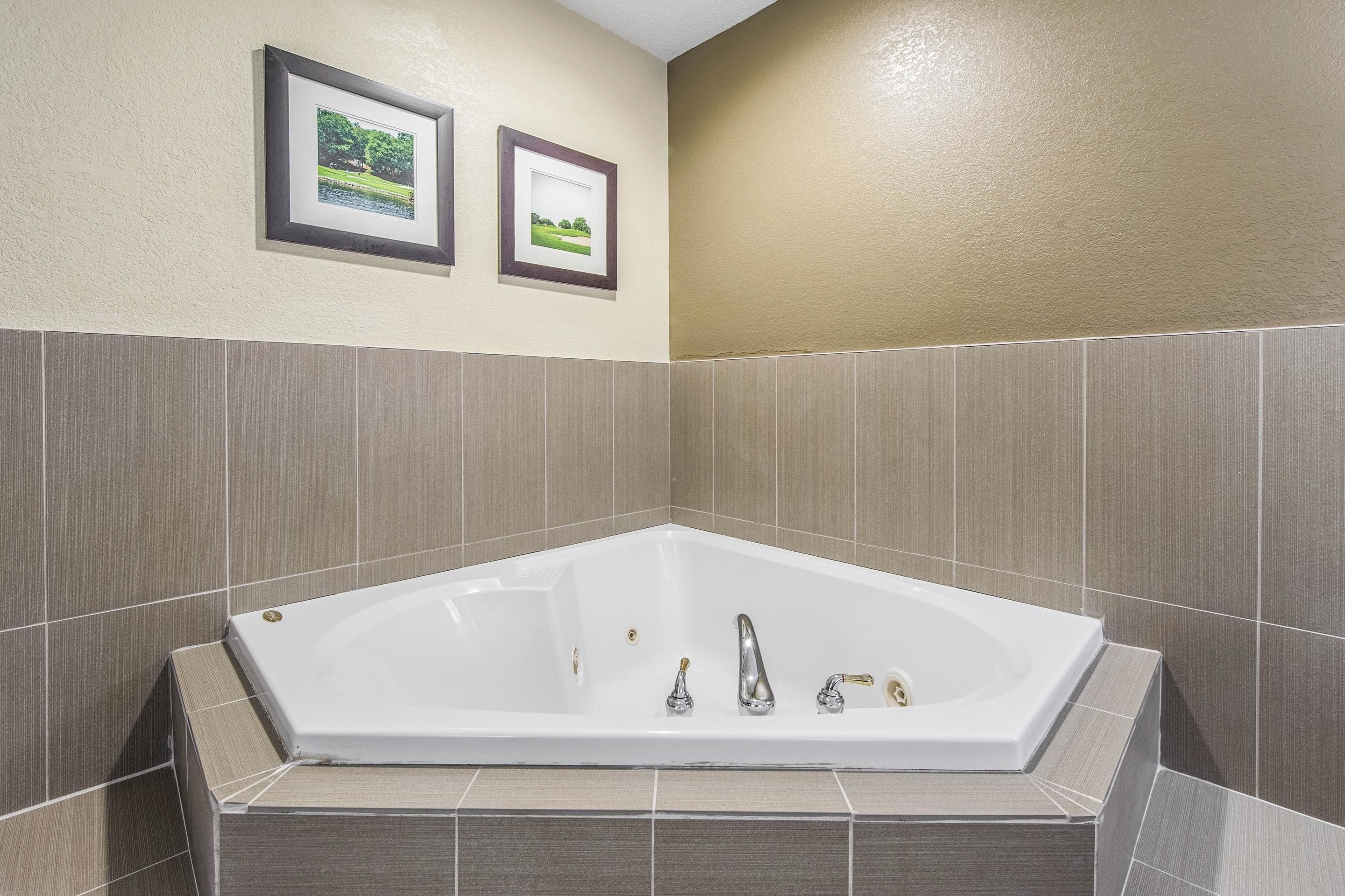 A modern bathroom with a freestanding bathtub, tiled walls, and framed pictures on the wall.