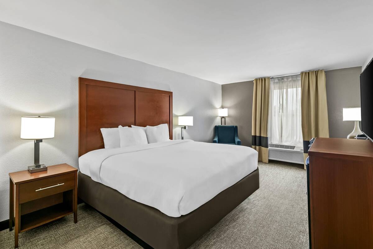 A hotel room with a large bed, two bedside tables with lamps, a desk, and a television.