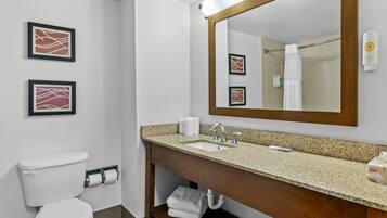 A bathroom with a toilet, sink, mirror, and towel rack.