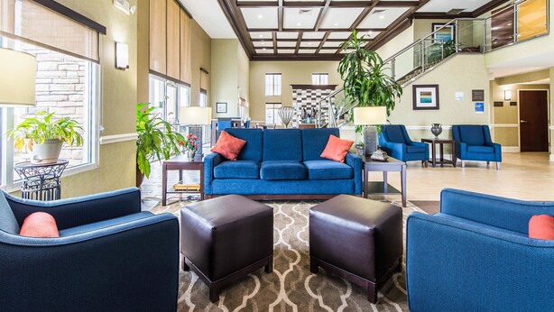 Un hall d’entrée spacieux avec un canapé bleu, des fauteuils et un escalier.