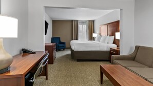 Une chambre d’hôtel équipée d’un lit, d’un bureau, d’une chaise, d’un canapé et d’une télévision.