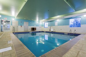 An indoor swimming pool with clear water, marked lanes, and safety signs.