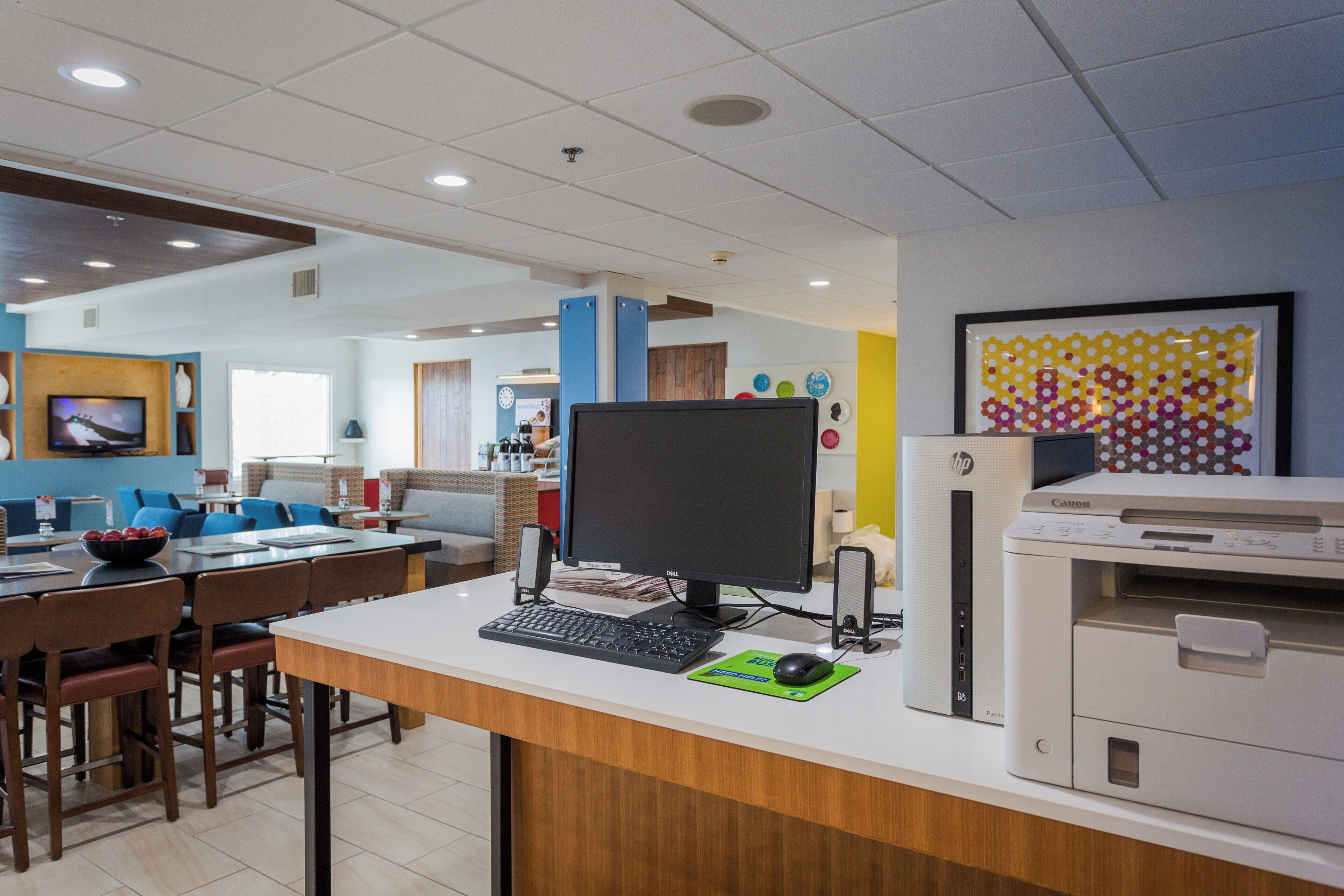 Een moderne kantoorruimte met een bureau, computer, printer en zithoek.