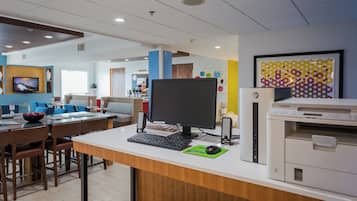 Een moderne kantoorruimte met een bureau, computer, printer en zithoek.