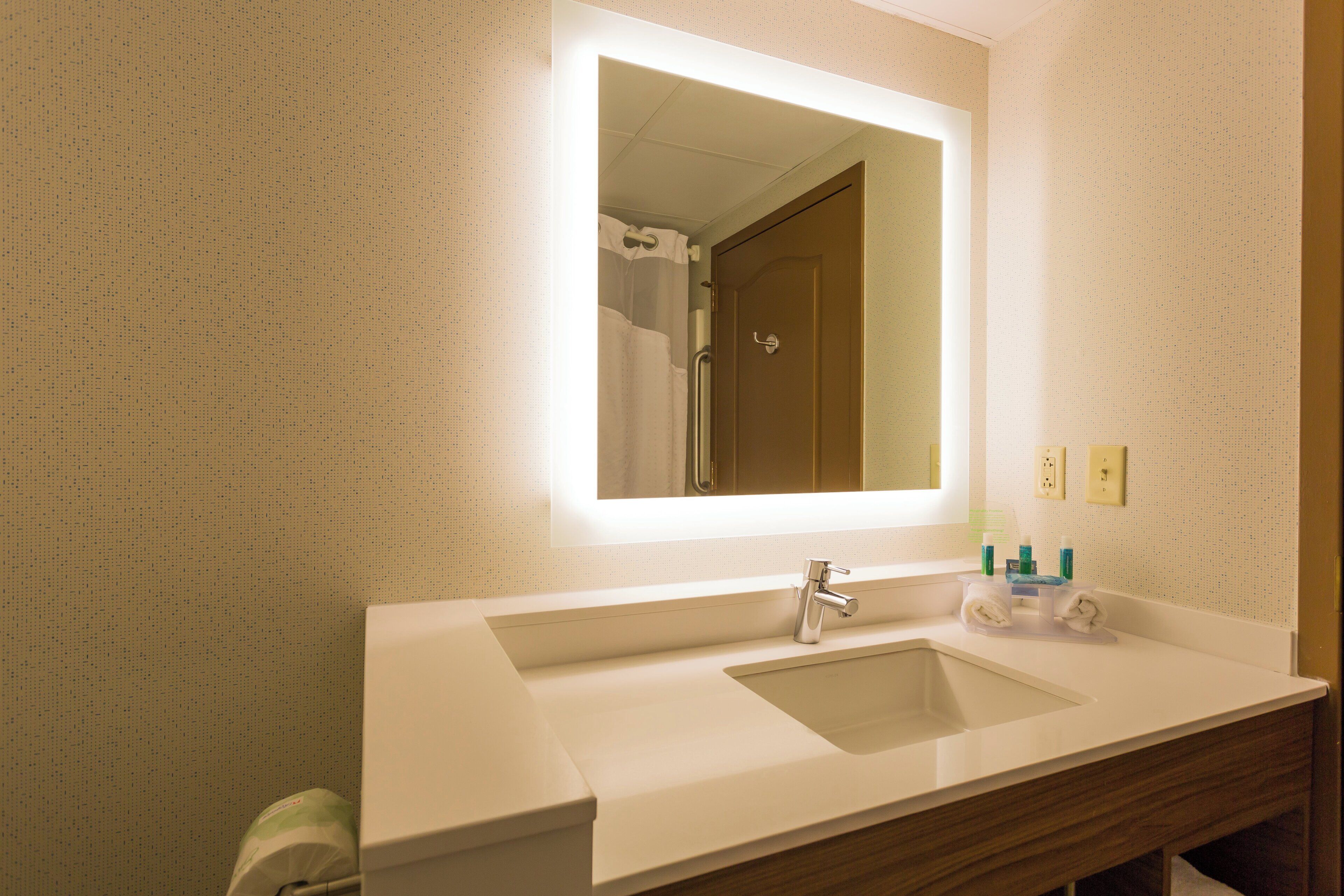 A bathroom with a double sink, a mirror, and a shower visible in the reflection.