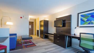 Una habitación de hotel moderna con escritorio, silla, televisión y una alfombra colorida.
