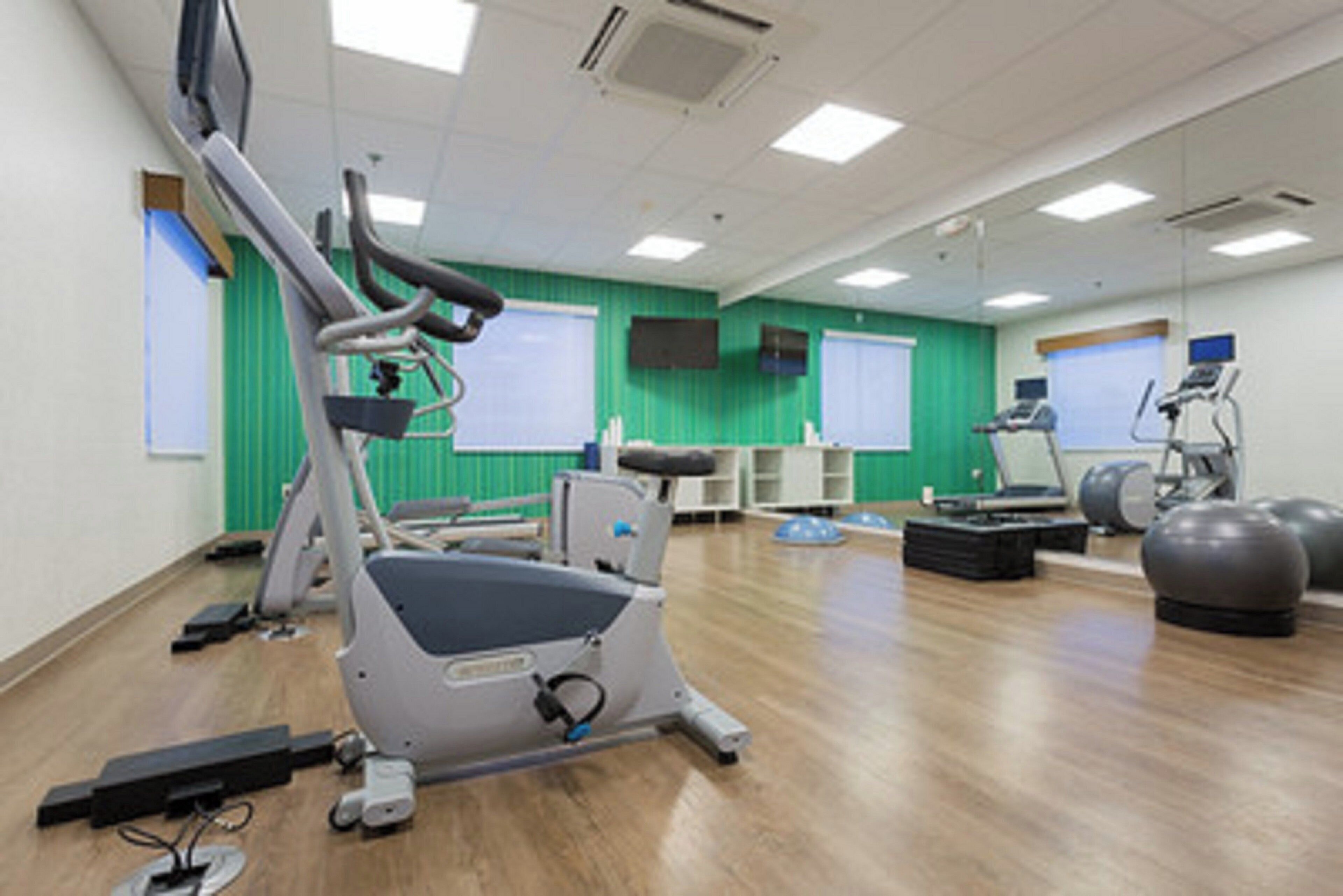 A fitness room with exercise equipment, including a treadmill, stationary bike, and exercise balls.