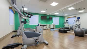 A fitness room with exercise equipment, including a treadmill, stationary bike, and exercise balls.