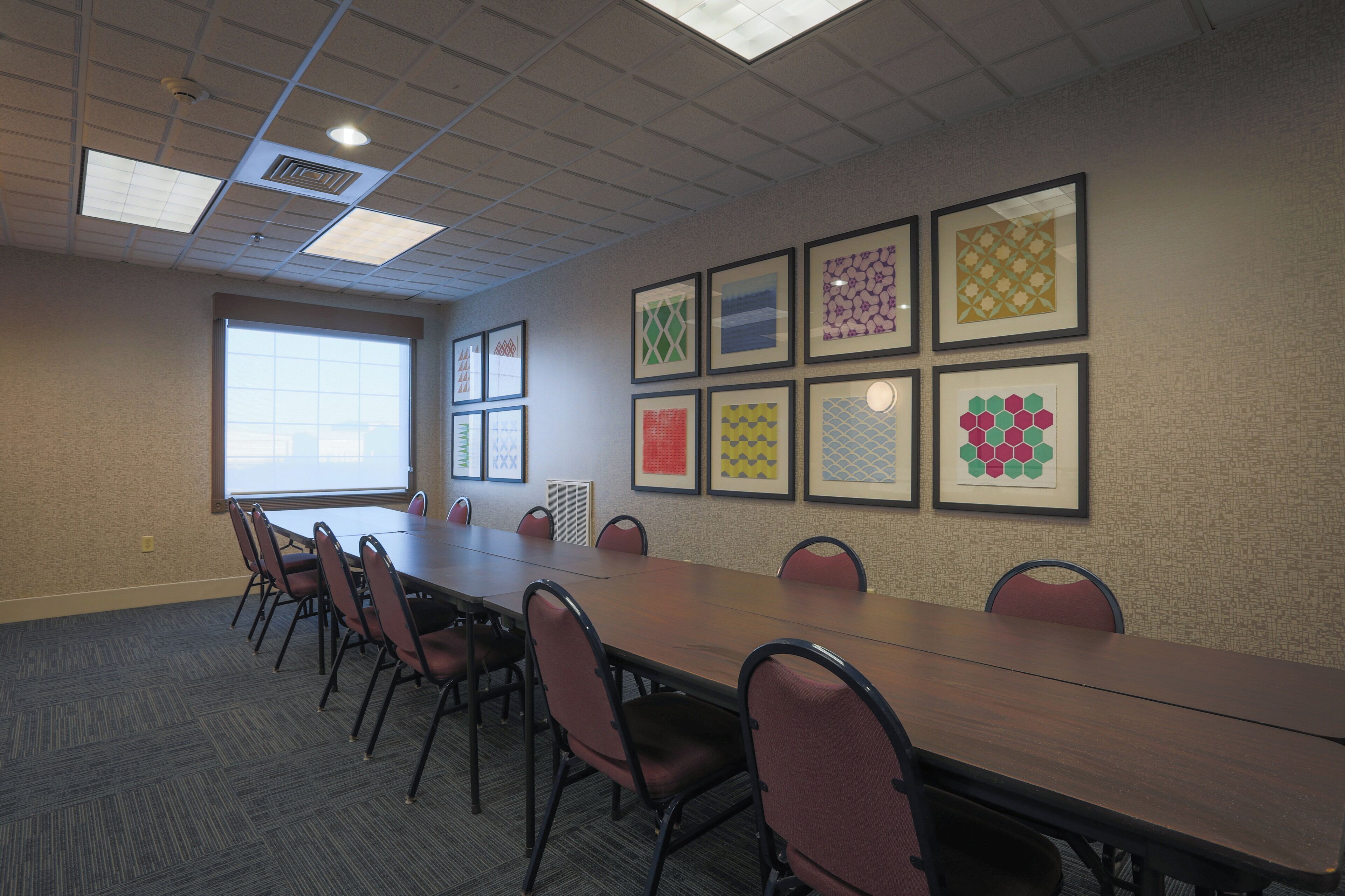 A conference room with a long table, chairs, and framed artwork on the wall.