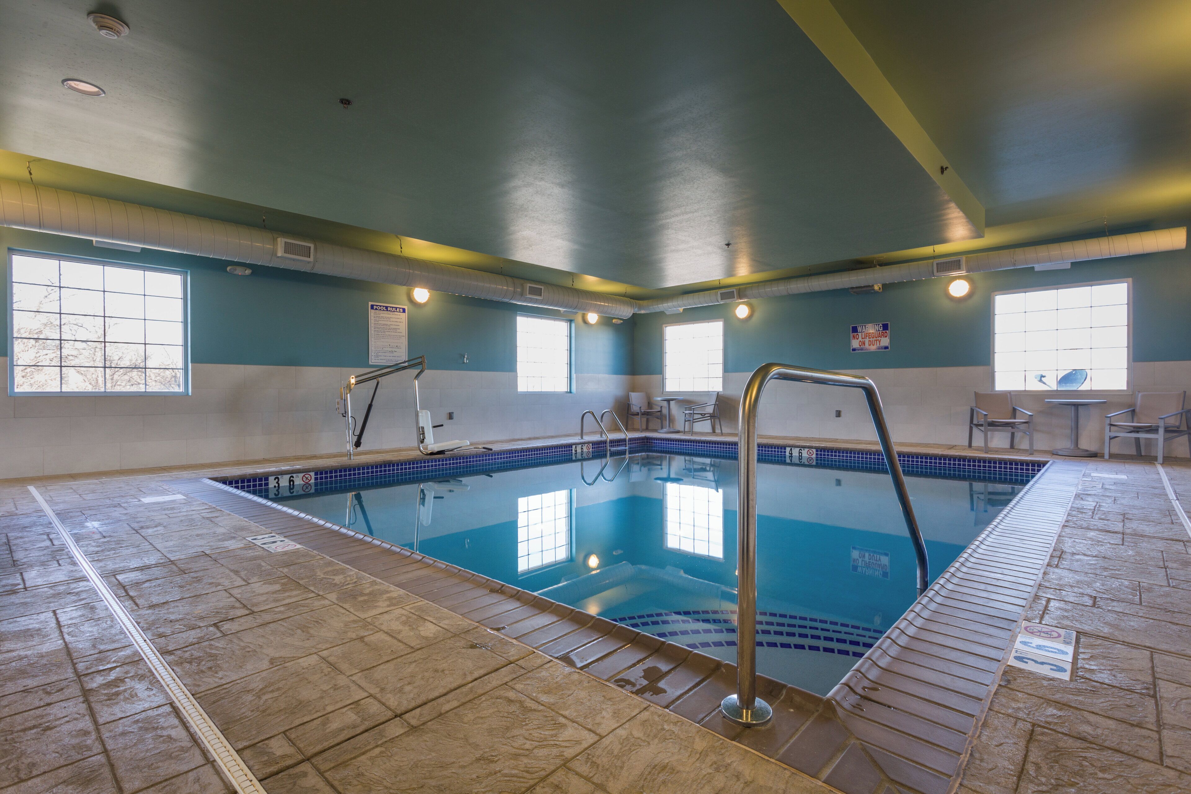 An indoor swimming pool with clear water, tiled walls, and a lifeguard chair.